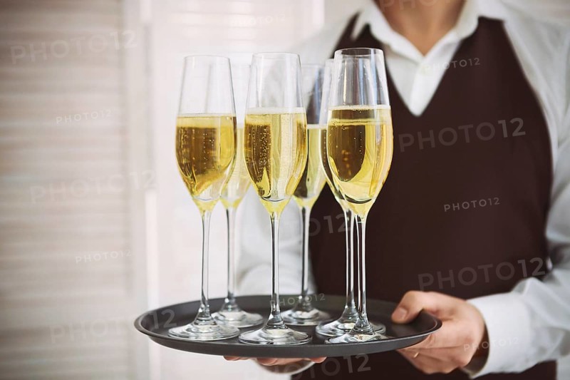 Professional male waiter in uniform serving champagne. DOF. Natural light. Photo in motion