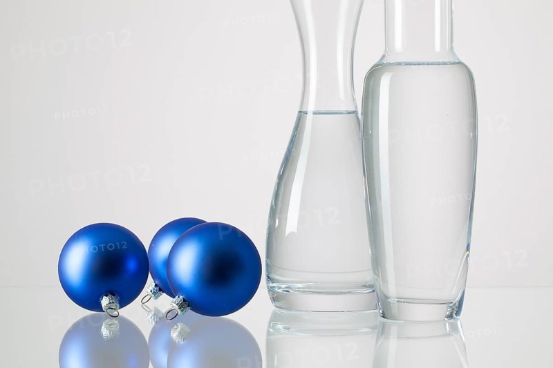Two vases with clean water and Christmas decoration on a glass table
