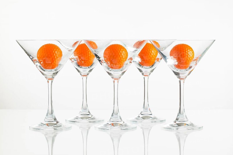 Five glasses of champagne and golf equipments on the glass desk
