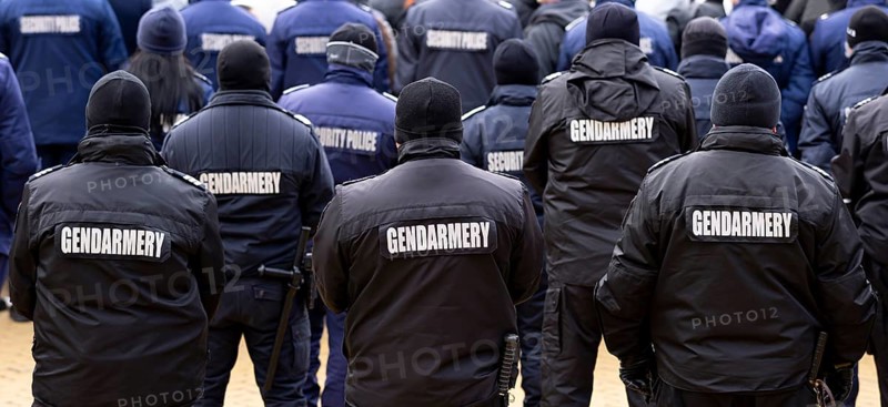 Police officers are seen from their backs. Unrecognizable policemen and policewomen. Gendarmery