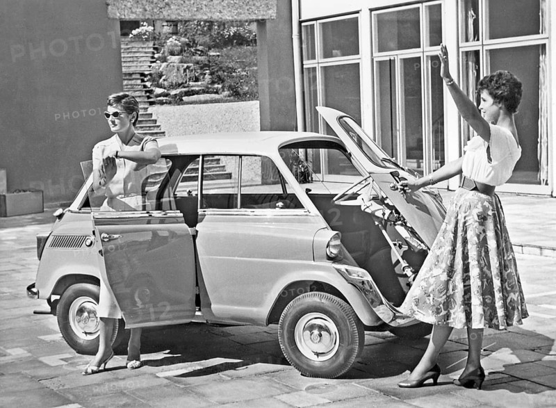 Driving in the 1950s. Two young women is standing beside a car model BMW 600. A micro car model with the front door really in front. 1958