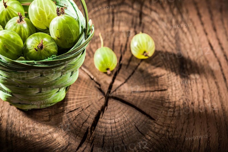 Fresh gooseberries in basket on vintage wooden board