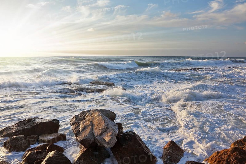 Magnificent sunset on Mediterranean sea. Storm waves break about breakwater stones on quay. Tel Aviv, spring