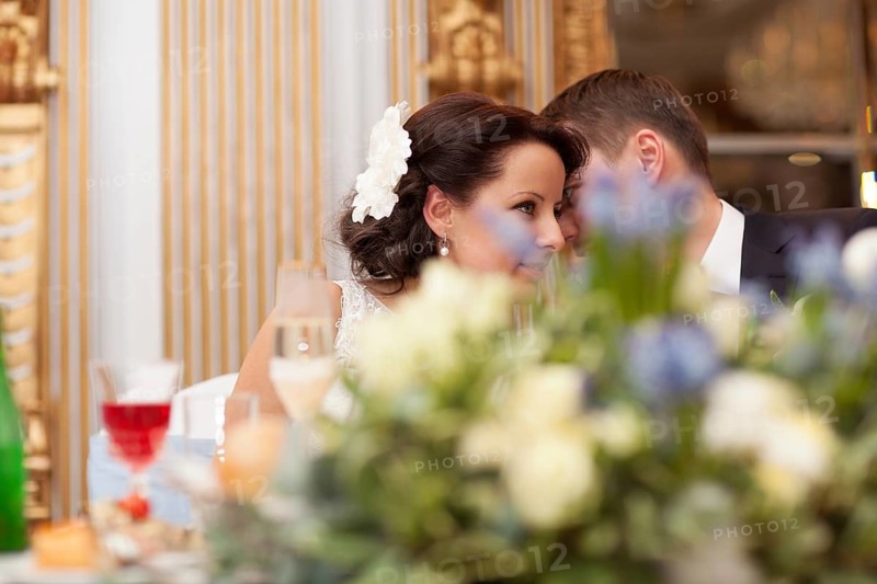Bride and groom sharing a special tender moment at the wedding leaning with their heads close together as they share their love, view across a bowl of flowers