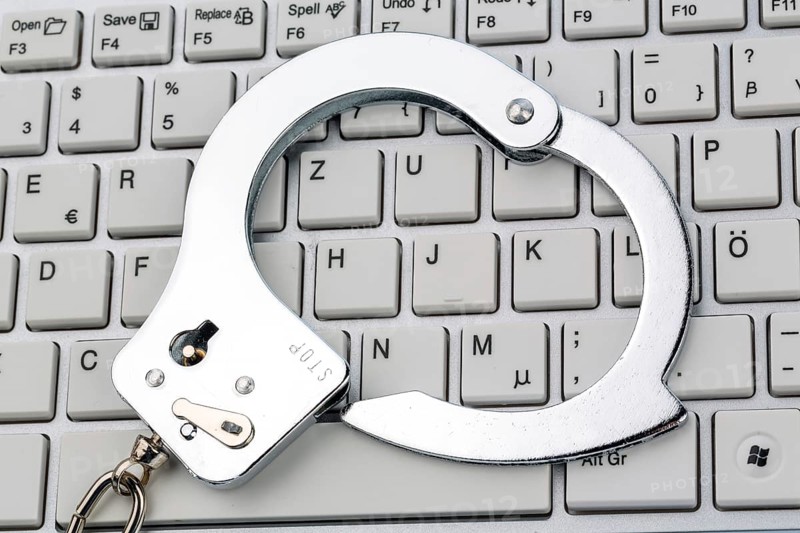 Handcuffs lying on the keyboard of a computer. Symbolic photo for criminality, computer crime and data misuse