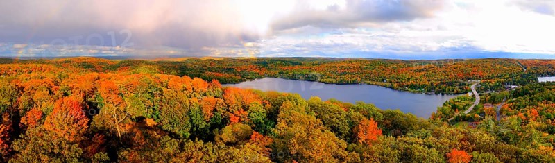 Aerial panoramic view of Lake of Bays and colorful fall forest during sunset with a trace of a rainbow. Dorset Ontario Canada