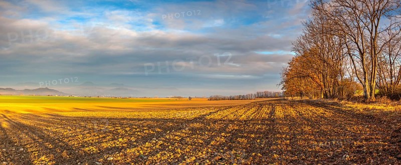Autumn morning landscape over the city of Louny. Autumn plowed field at amazing sunrise. Czech Republic. Panorama image