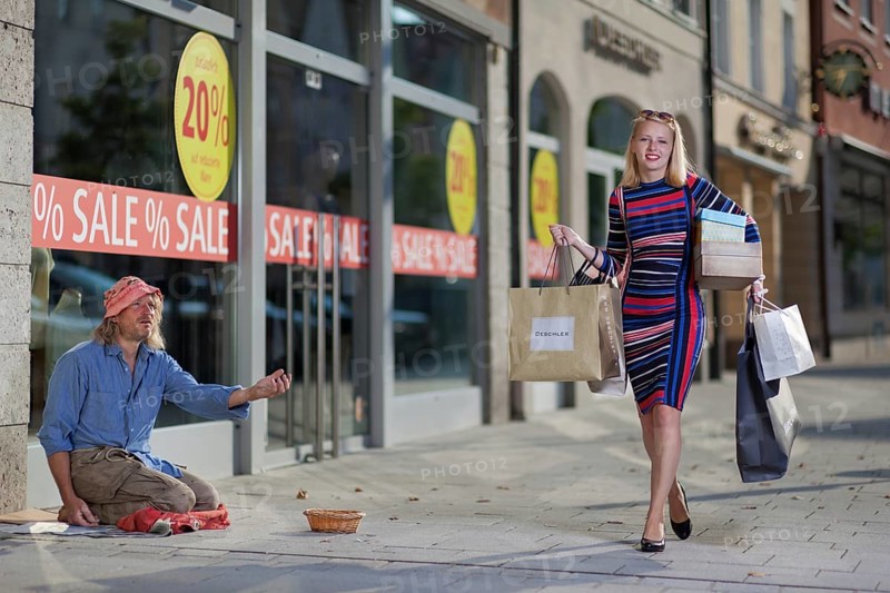 Woman with shopping bags walks past a homeless man on the street, Staged photo shoot, Mindelheim, Unterallgäu, Bavaria, Germany