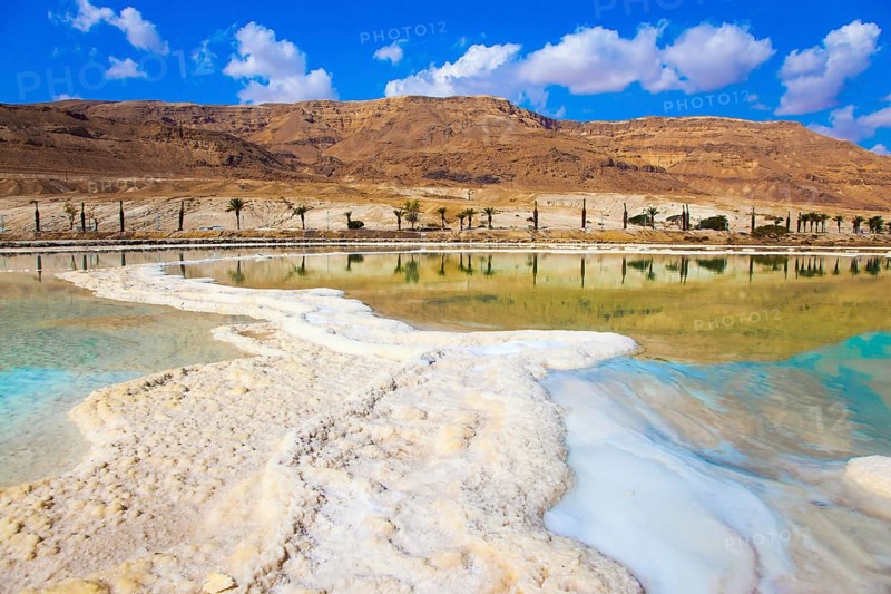 Therapeutic Dead Sea, Israel. The evaporated salt is precipitated by picturesque stripes in shallow water. The concept of medical and ecological tourism