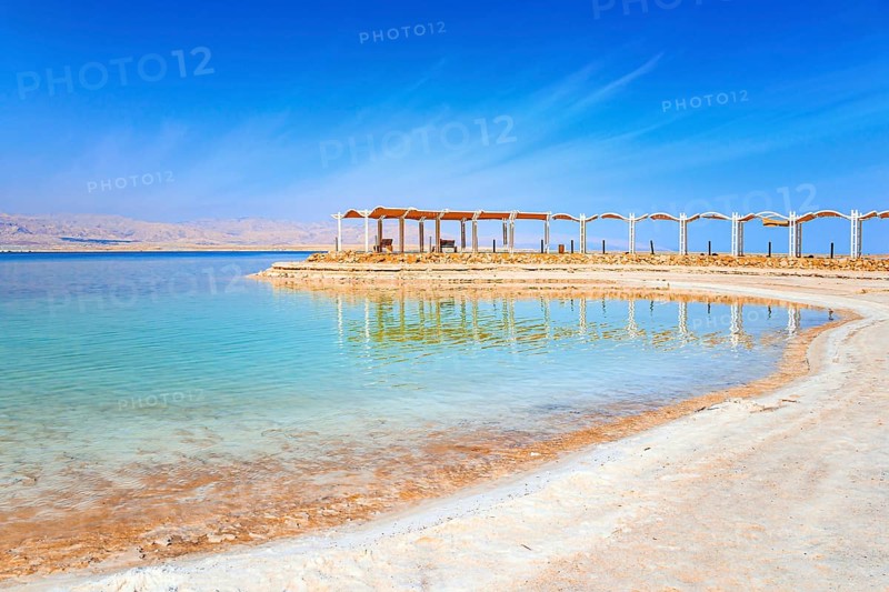 The drainless salt lake in the Middle East. Dead Sea. Israel. Evaporated salt forms ?rystals on the surface of the water. Special awning on the beach to protect from the sun