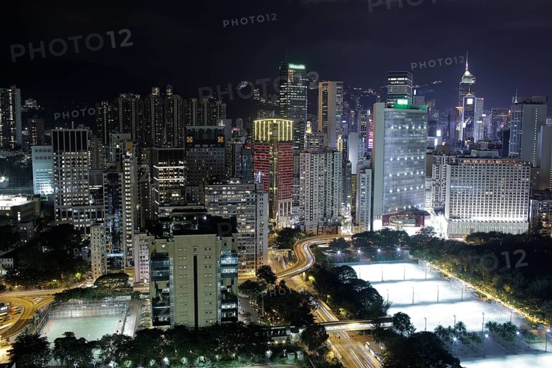 Illuminated Hong Kong. Night city view with concrete jungle, road interchange and football fields