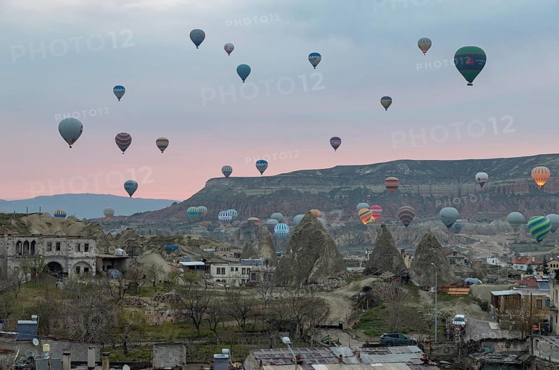A picture of hot air balloons flying over the Goreme Historical National Park and the town of Goreme at sunrise