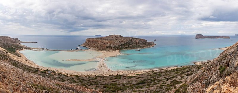 A panorama picture of the blue water of Balos Beach and the nearby landscape of the Gramvousa Peninsula