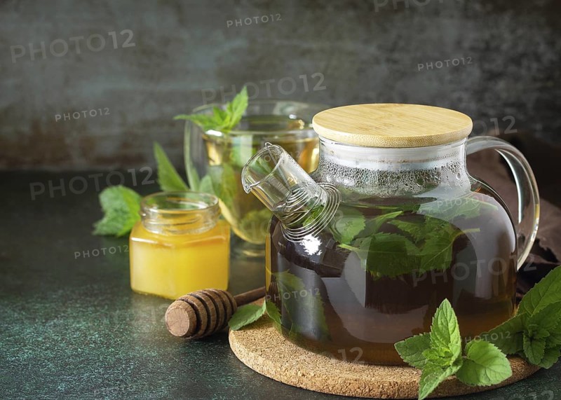 Therapeutic herbal green tea. Hot tea with honey mints in a glass teapot on a stone table. Copy space