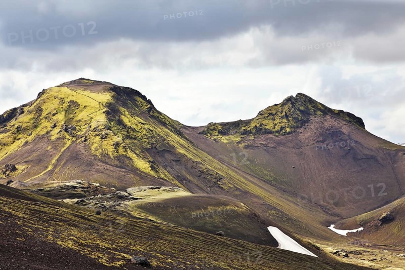 National Park Landmannalaugar in July. Green and pink mountain slopes and snowy white residues from last winter