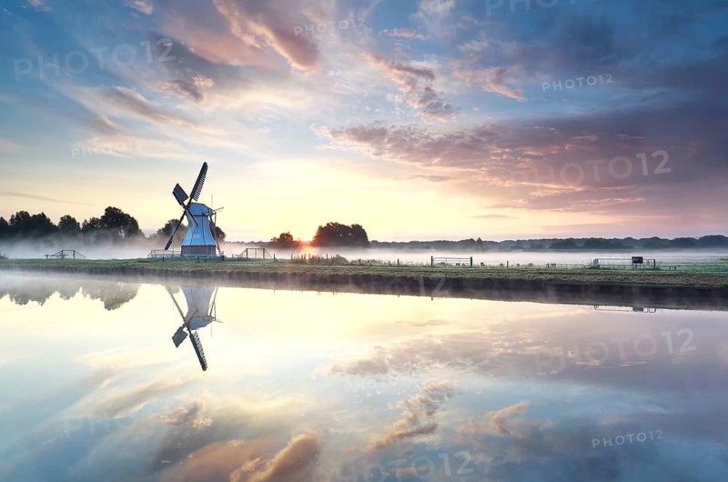 Golden sunrise over windmill reflected in river, Netherlands