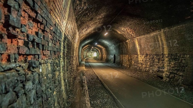 Walking through the Headstone Tunnel, near Monsal Head in the East Midlands, Derbyshire, Peak District, England, UK
