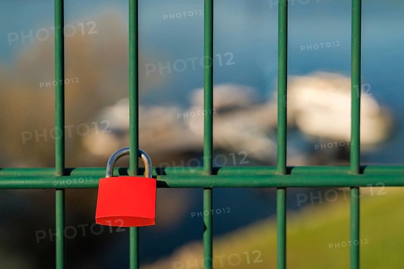 Love lock and grid of the lift bridge Walsum in Duisburg, North Rhine-Westphalia, Germany, with some blurry boats in the background
