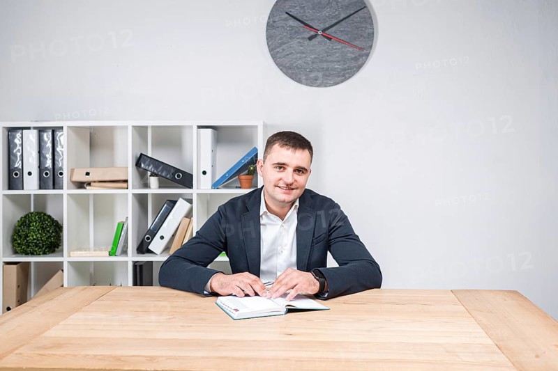 Portrait of a Caucasian male indoors posing in a jacket and white shirt. Overweight office worker at the workplace. The topic of obesity in sedentary inactive work. Fat business man