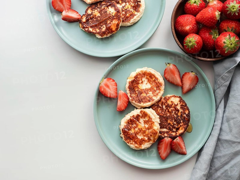 Sweet cheese pancakes on plate served strawberries. Cottage cheese pancakes, syrniki, ricotta fritters, curd fritters. Top view or flat lay. Copy space for text or design
