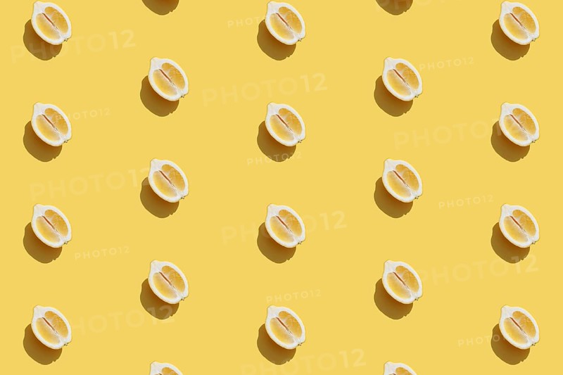 Conceptual pattern with halves of lemon collection with shadow on yellow background. Healthy eating, travel or vacation concept