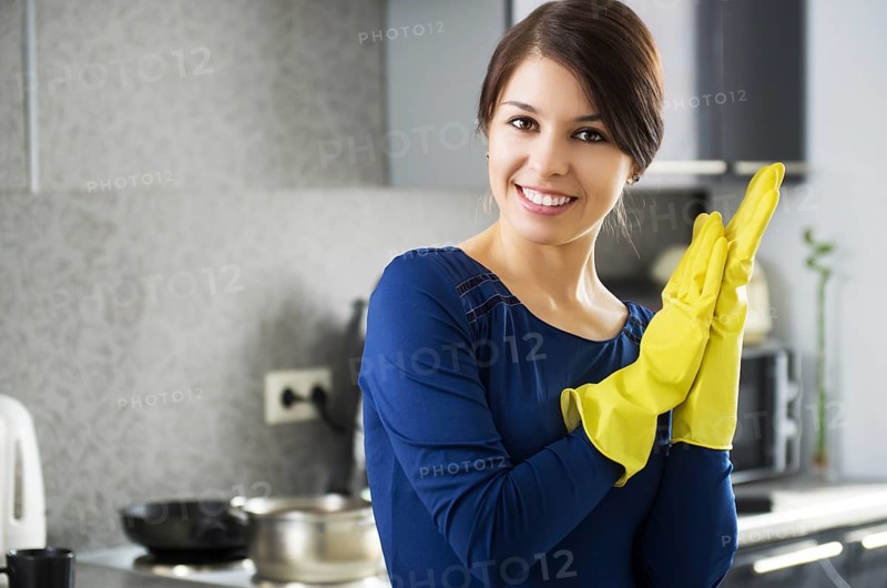 Portrait of young attractive caucasian brunette housewife at kitchen wearing the yellow rubber gloves