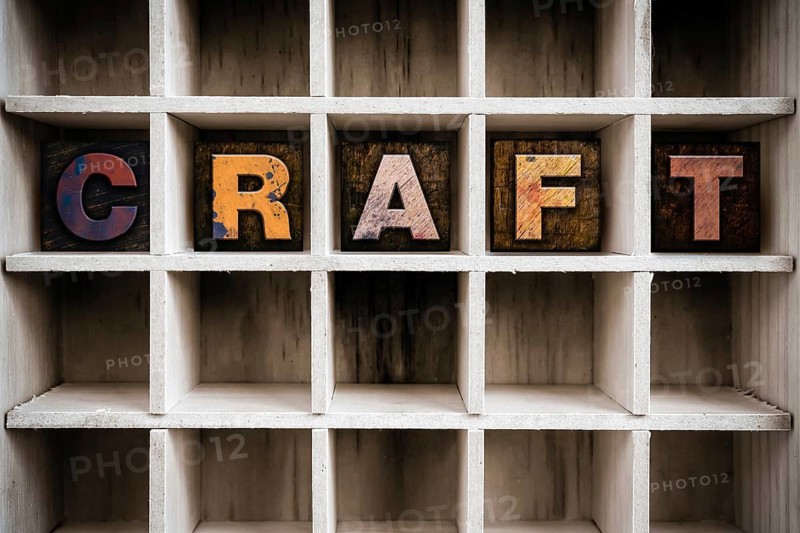 The word CRAFT written in vintage ink stained wooden letterpress type in a partitioned printer's drawer