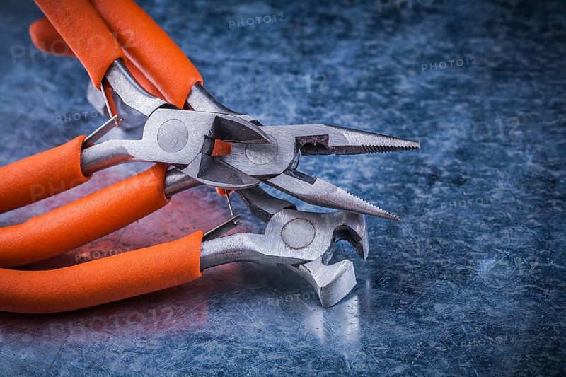 Set of insulated electric pliers nippers on scratched metallic background
