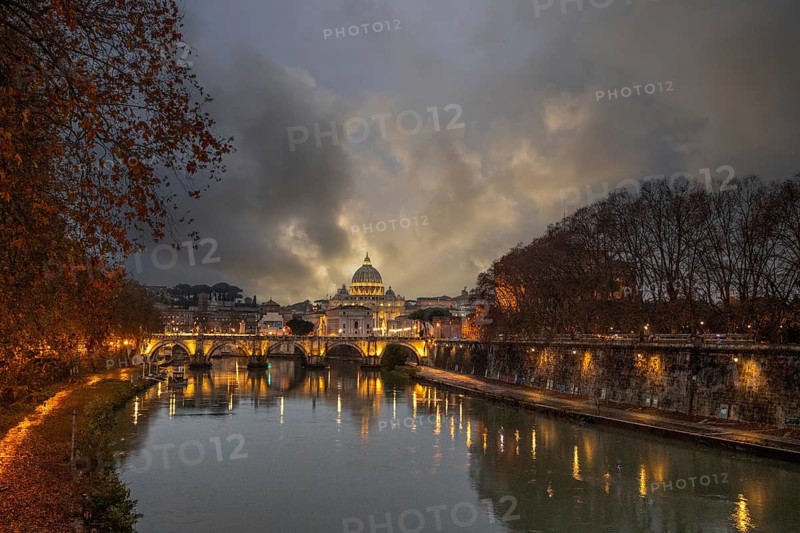 View over the river Tiber in a historic city. The old famous bridge Ponte Sant'Angelo, in the evening. Rainy weather at sunset and view of the Basilica of San Pietro, Rome, Italy