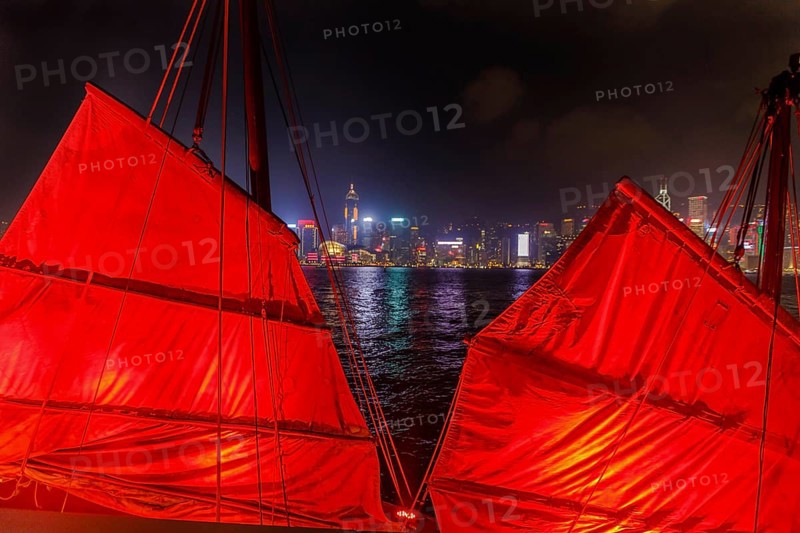 Close up of red-sail junk boat with Hong Kong island skyline background seen from the waterfront of Tsim Sha Tsui in Kowloon