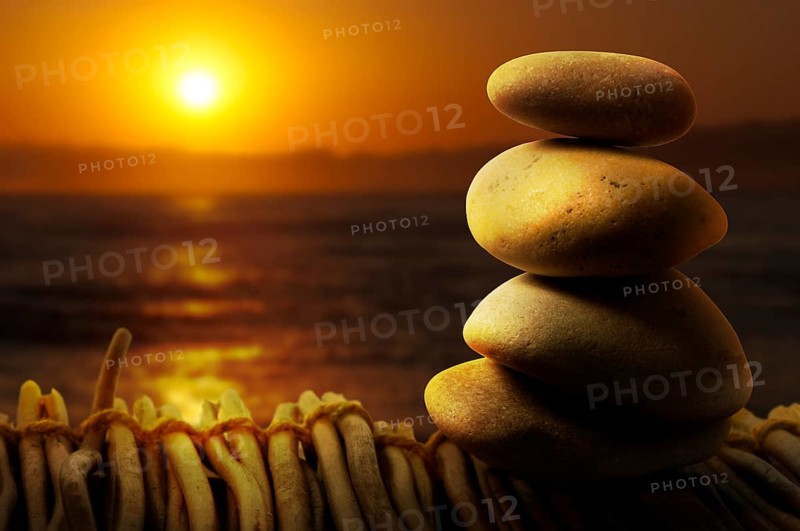 Stacked stones on wooden base for spa. Sunrise background