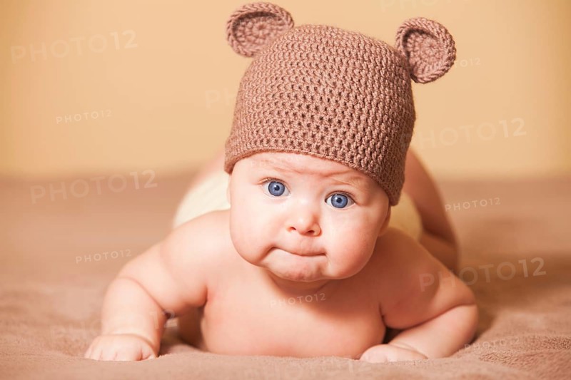 Adorable baby in bear hat lying on the bed