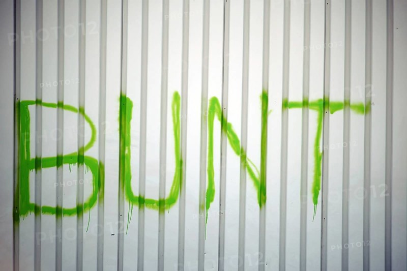 The detail of a corrugated iron façade colourfully painted with the slogan