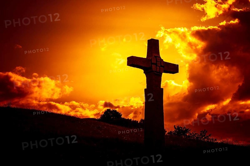 An image of a stone cross in front of a dramatic evening sky