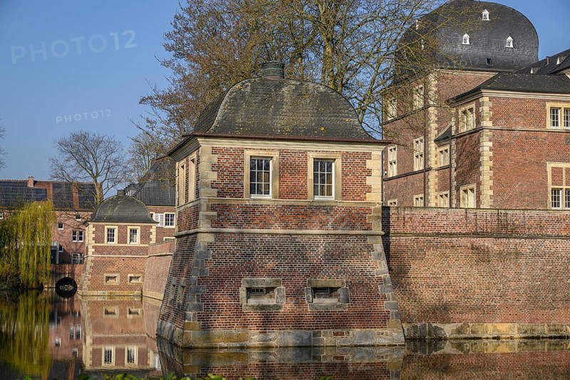A pavilion and a brick castle reflected in the calm waters of a moat, ahaus, münsterland, germany