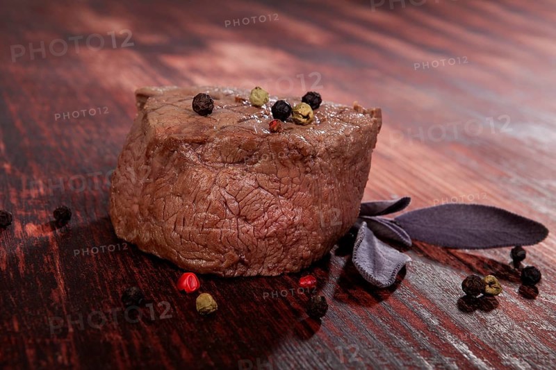 Luxurious sirloin steak on wooden background with peppercorn and herbs. Culinary red meat eating. Gourmet steak