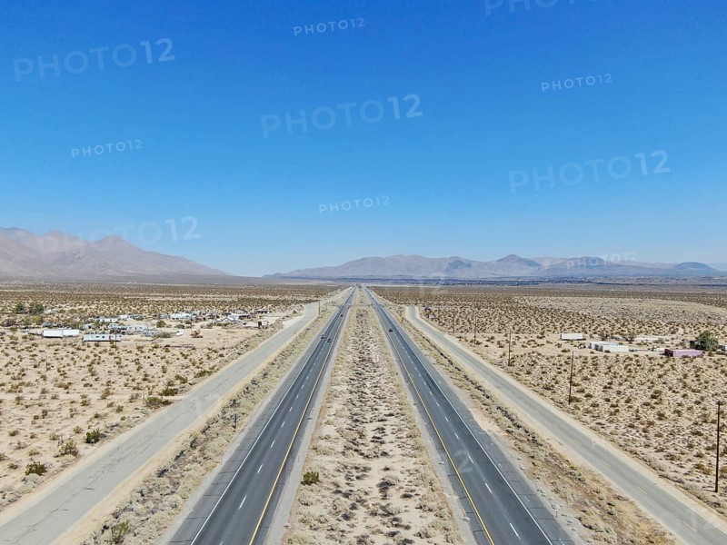 Aerial view of road in the middle of the desert under blue sky in California's Mojave desert, near Ridgecrest. Desert brush with road