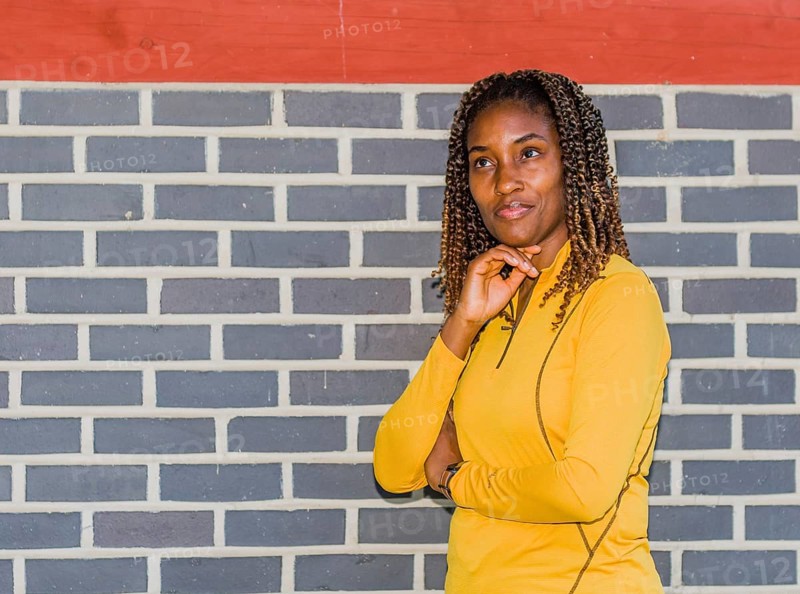 Young black woman in yellow with curly hair posing against a brick wall, Taken in Daejeon, South Korea