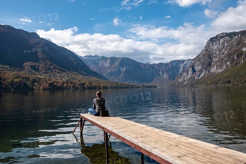 Sitting on a small jetty and enjoying the view on the landscape of lake Bohinj in the Triglav National Park, The Julian Alps, Slovenia