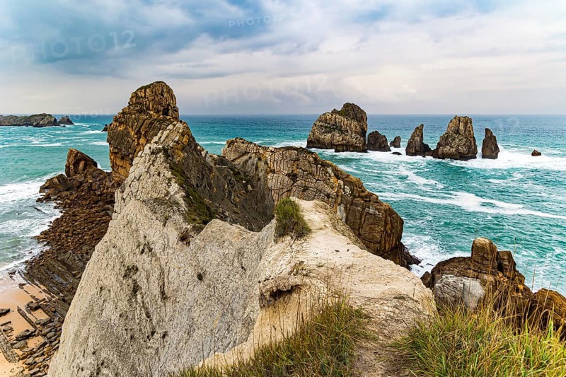 Picturesque cliffs and huge stones oppose the ocean. Spanish coast, Cantabria. Rocky coastline of the Atlantic Ocean. Stormy autumn day in the Bay of Biscay. Portio beach