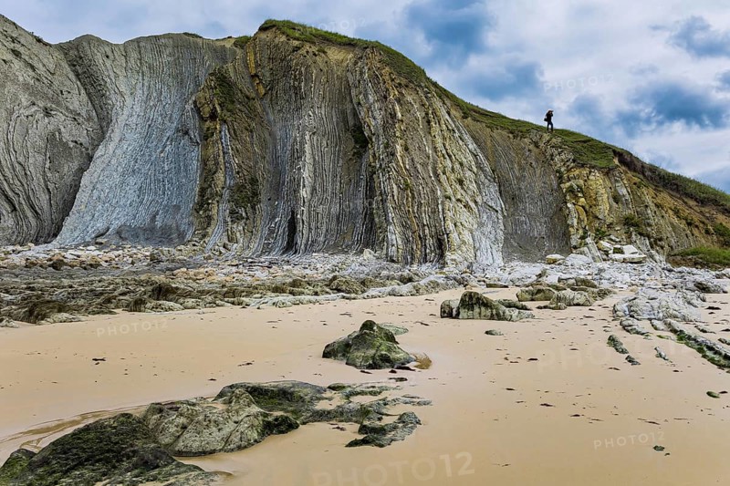 Noon on the beach of Playa di Arnia, Spain. Rocky picturesque ocean coast. Cantabria. Windy stormy day on the Atlantic coast. Photographer photographs a stunning landscape