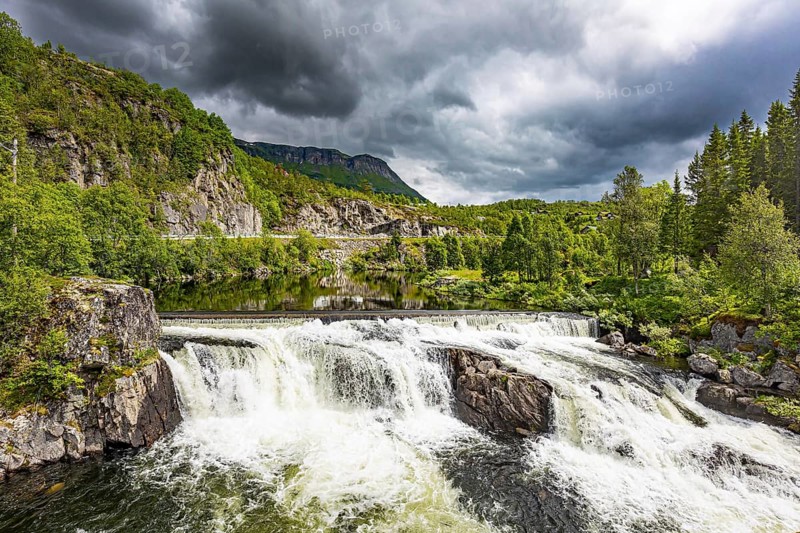 Magnificent seething waterfall - the threshold on the river Bioreio. The interesting trip to the Scandinavian Peninsula. The green shores are reflected in the smooth water