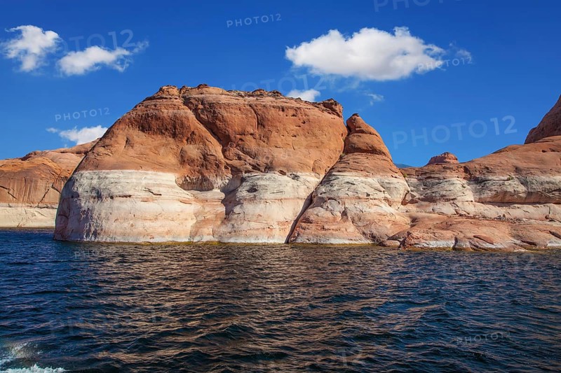 Picturesque artificial huge reservoir Powell on the river Colorado, USA. The lake is surrounded with picturesque coast from orange sandstone. Walk on the lake Powell on a sunset