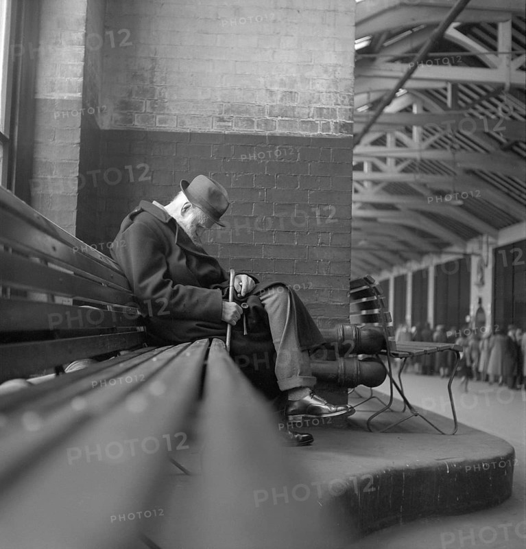 London in the 1950s. Older man sits on a bench with his pipe and stick in his knee, London 1952