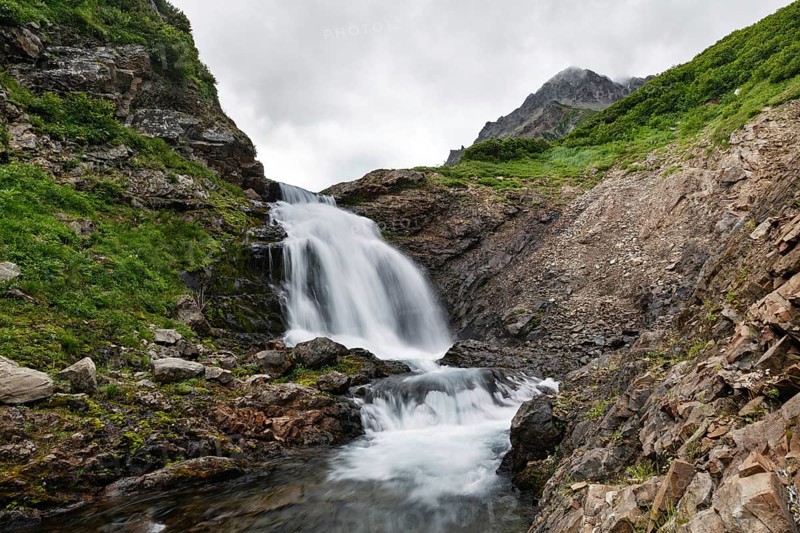 Summer mountain landscape of Kamchatka: beautiful view of picturesque waterfall in Mountain Range Vachkazhets. Eurasia, Russian Far East, Kamchatka Peninsula