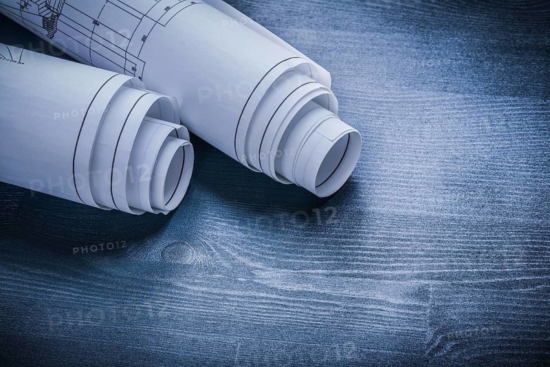Rolled white blueprints on wood board
