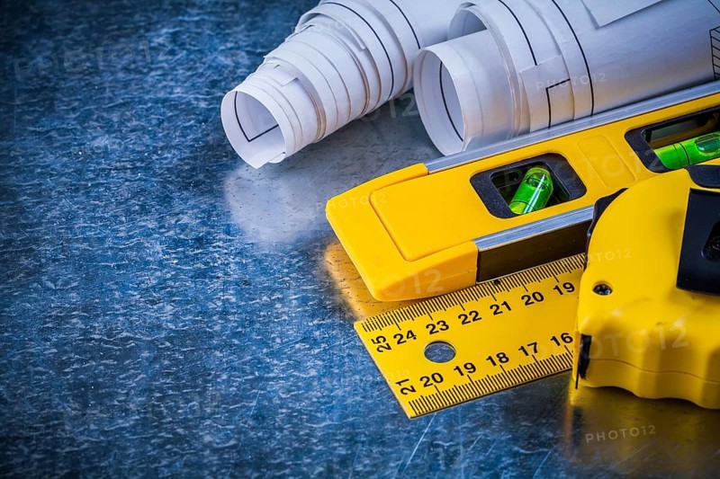 Ruler measuring tape construction level and blueprints on metallic scratched background building and architecture concept