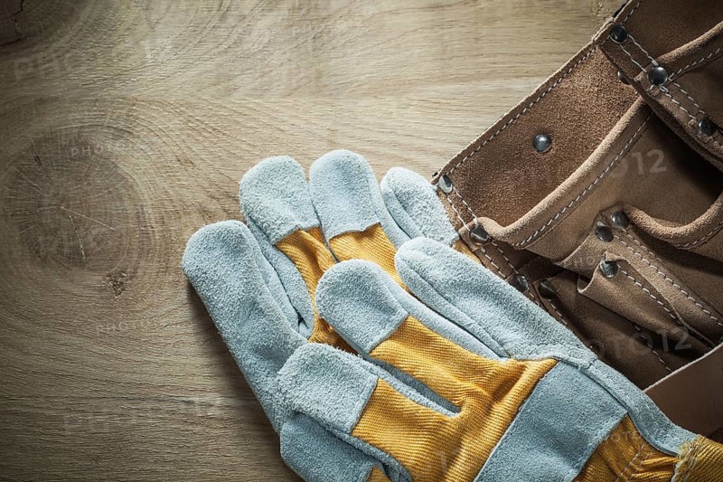 Leather building belt safety gloves on wooden board
