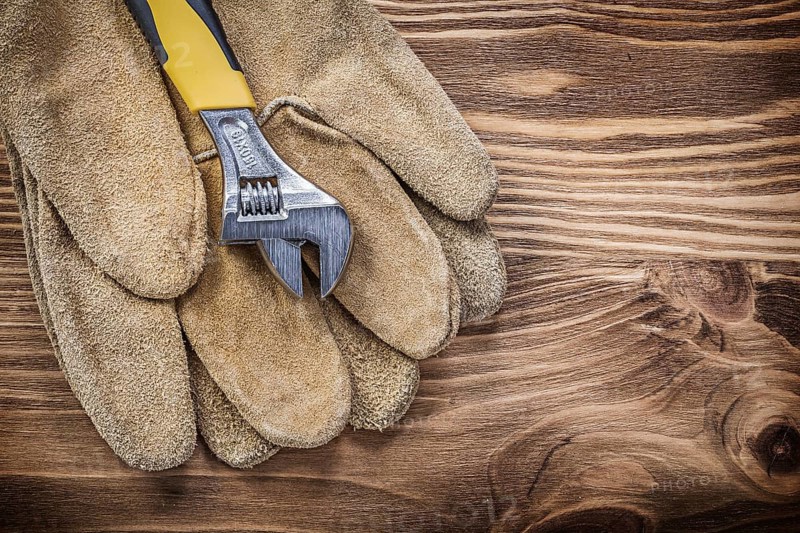 Safety gloves adjustable wrench on wooden board construction concept