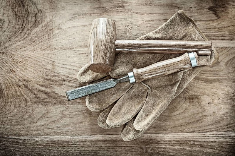 Wooden hammer chisel protective gloves on wood board